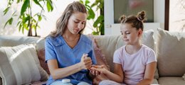 A young woman helping a girl with her diabetes treatment