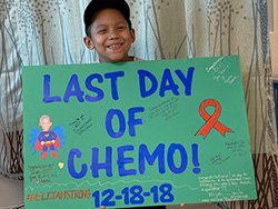 Eli holding up a sign celebrating his last day of chemo