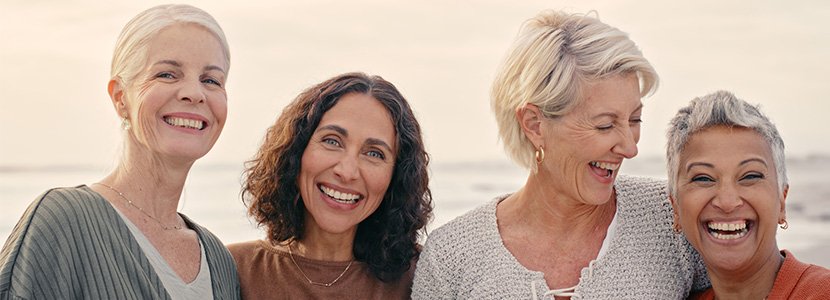 a group of 4 women smiling and enjoying a day at the beach