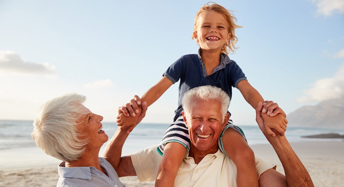 Seniors holding up a child at a beach