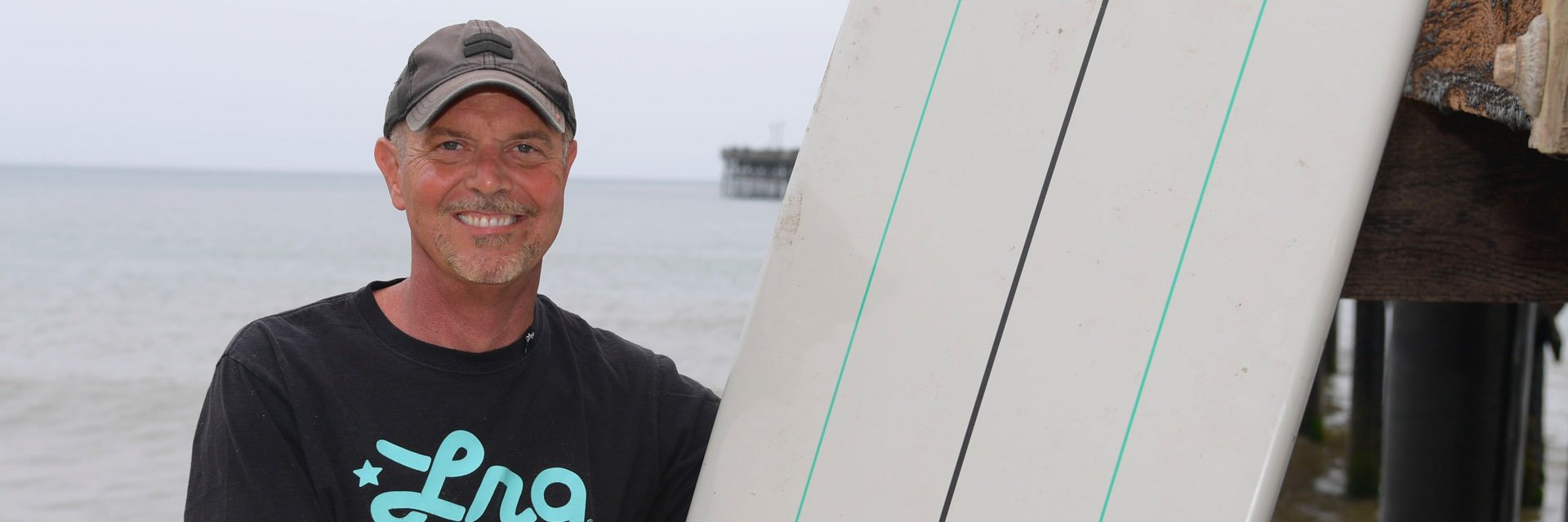 Male surfer holing a surfboard and smiling