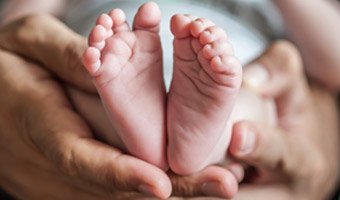 adult hands holding baby feet