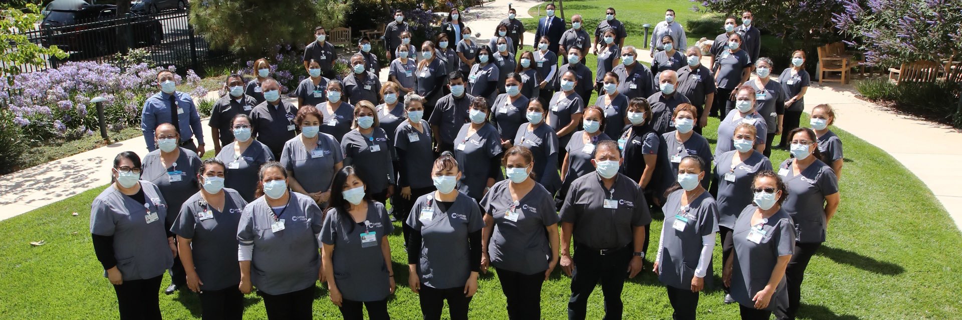Large group of Environmental Services workers posing for a photo outdoors