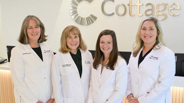 Group of doctors standing in front of a Cottage logo on a wall