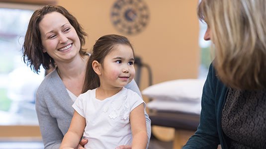 a woman holding her daughter in her lap meeting with a caregiver