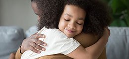 A mixed race girl embracing her father