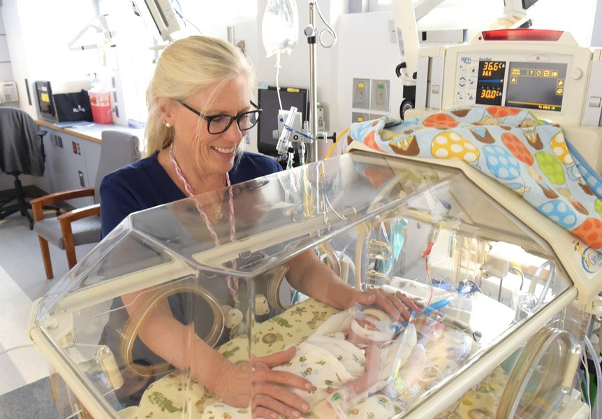 Provider attending to a newborn in an incubator