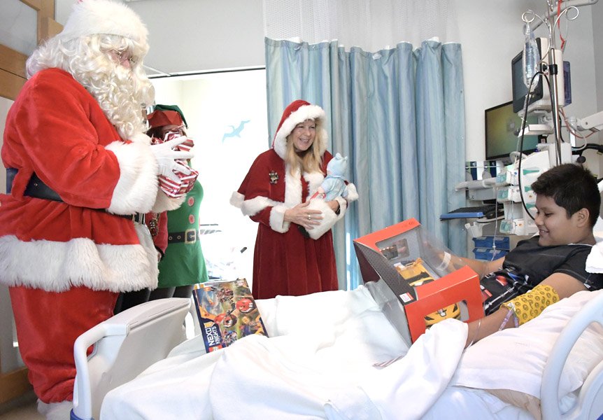 Santa giving a gift to a patient at Cottage Children's Medical Center