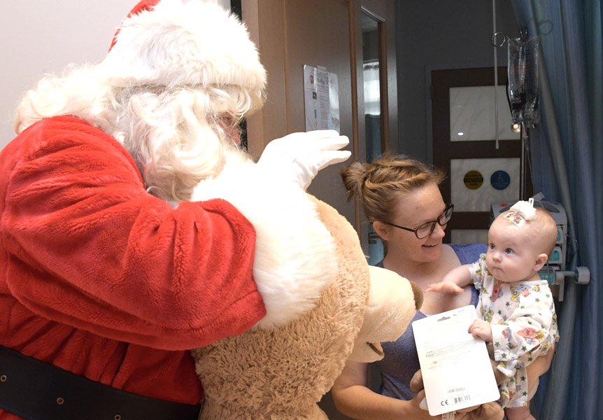 Santa paying a visit to a toddler at Cottage Children's Medical Center