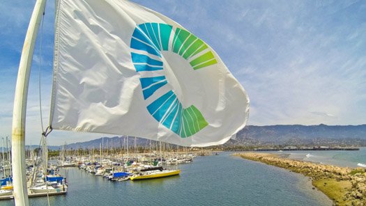 A flag with the Cottage Health logo flying over Santa Barbara Harbor