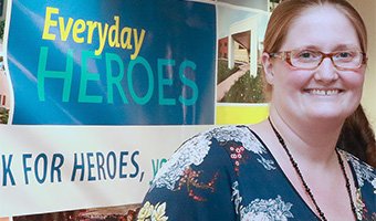 Everyday Heroes Award winner standing next to a banner