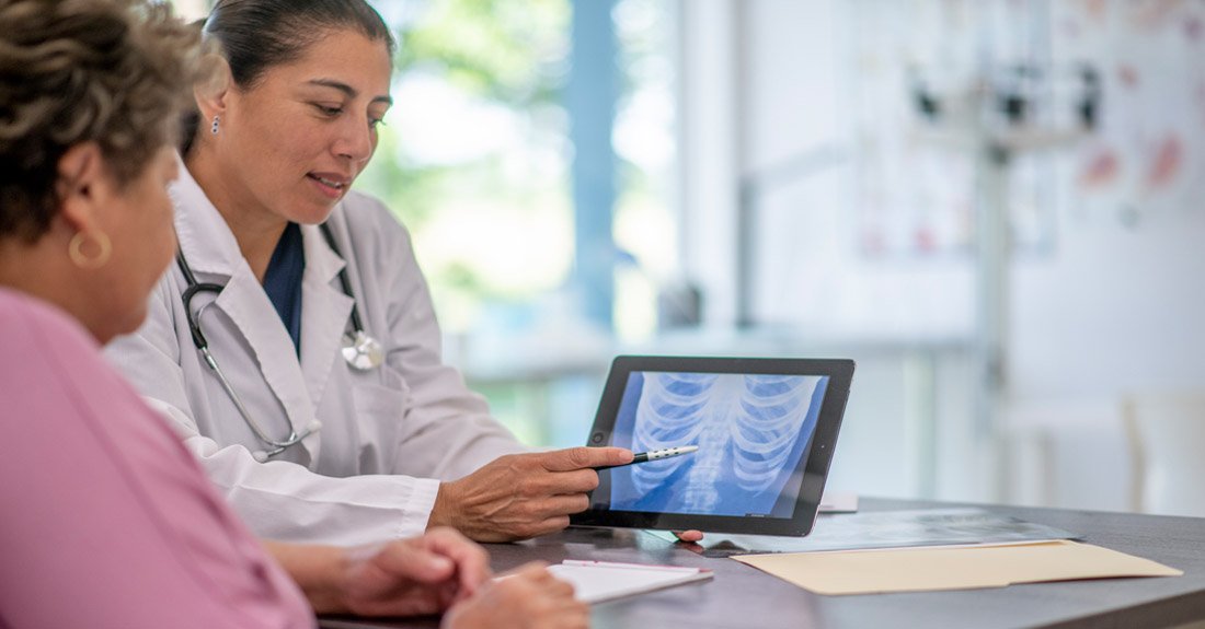 Doctor sitting with a patient reviewing imaging scans