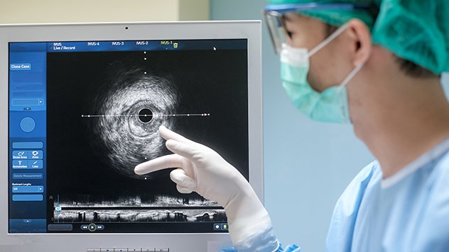a doctor in scrubs checking an ultrasound image monitor