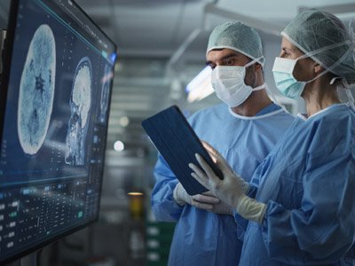Providers standing in front of computer screens reviewing brain scans