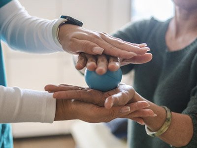 Photo of physical therpaist helping patient with therapy balls