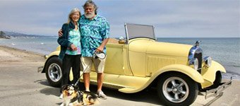 Bob Hawkins with his wife and dog standing in front of his yellow hot rod car