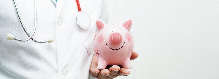 a medical student wearing a labcoat and stethoscope holding a piggy bank