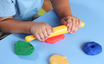 A child playing with a roller and playdoh