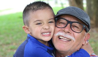 Child and grandfather hugging and smiling at the camera