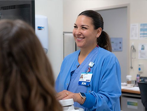 A cottage registered nurse in scrubs smiling and helping a patient