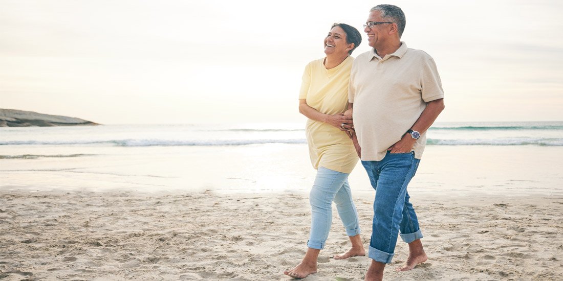 Middle aged couple walking arm and arm on the beach