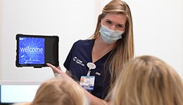 A clinical staff member showing patients information on a tablet